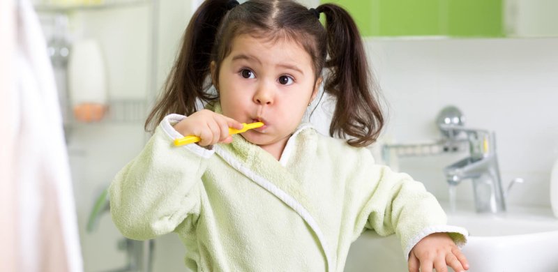 Child little girl brushing teeth in bath