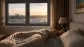 Persona durmiendo placidamente en una habitación con un ventanal al fondo y vistas de una carretera con tráfico